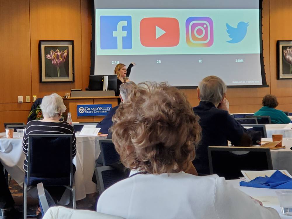 A woman points to a presentation with social media icons displayed